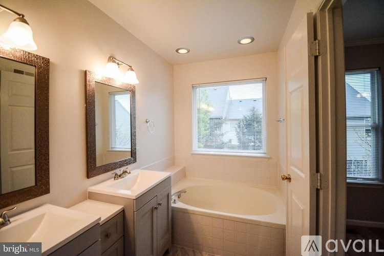A bathroom with a tub, sink, and mirror.