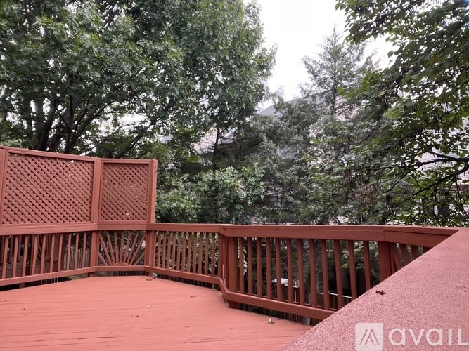 A wooden deck with lattice panels and a railing overlooking a wooded area.