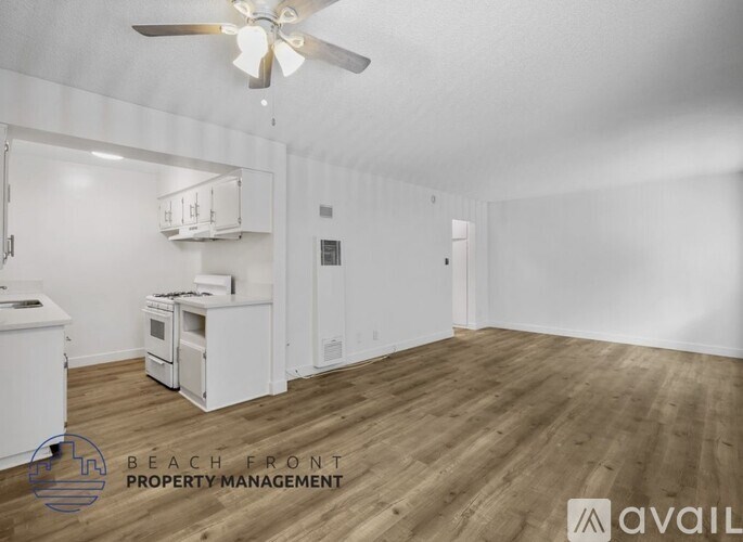 A spacious room with wooden flooring and a ceiling fan.