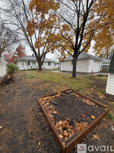 A backyard with a raised garden bed and trees.