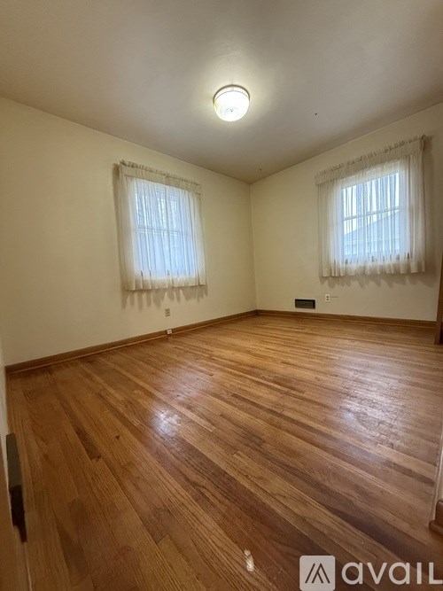 A room with wooden floors and two windows.