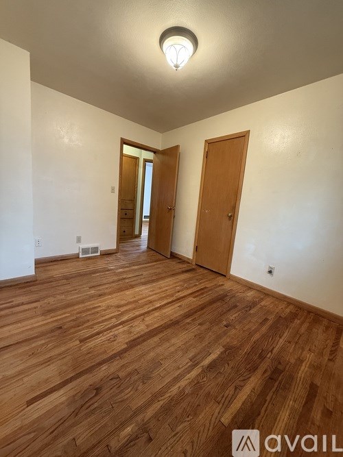 A room with wooden floors and two doors.