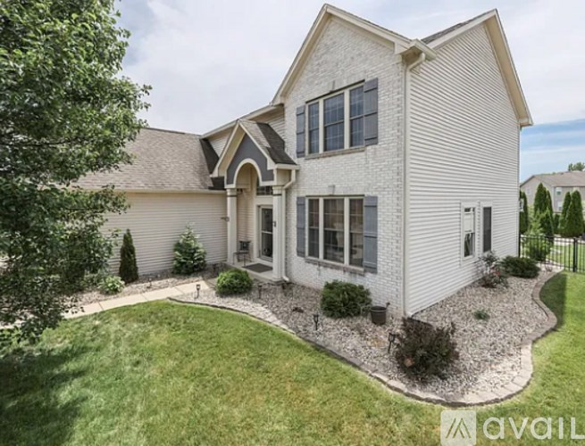 A house with a well-maintained lawn and landscaping is for sale.