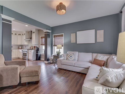 A living room with a white couch and a wooden floor.