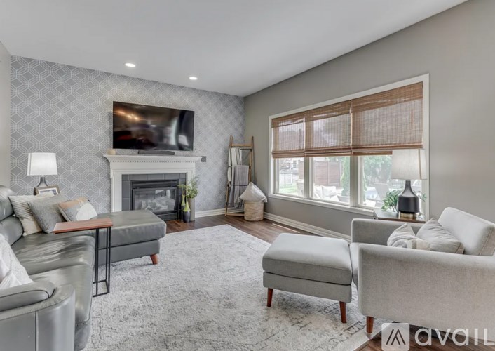 A living room with a grey sofa set, a fireplace, and a television mounted above it.