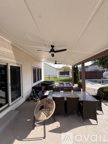 A patio with a table and chairs and a ceiling fan.