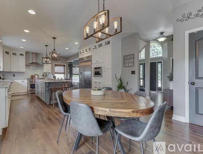 A modern kitchen with a wooden table and grey chairs.
