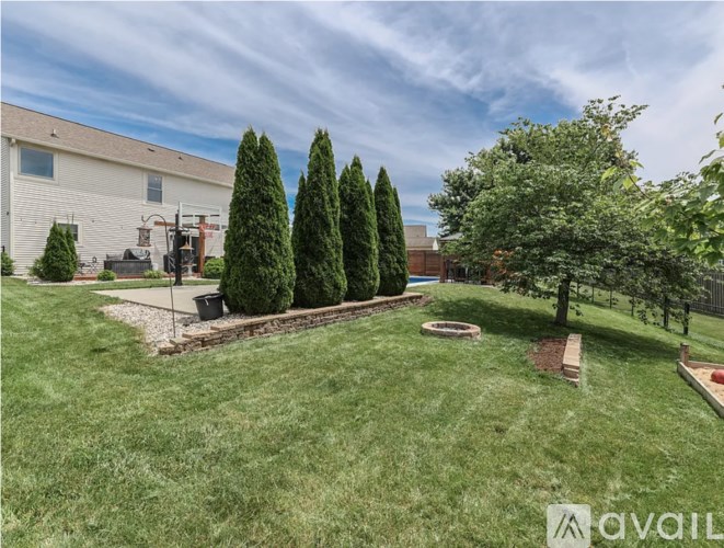 A backyard with a lawn, a small fire pit, and a tree.