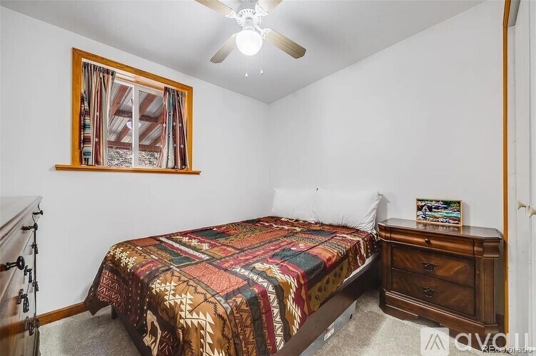A bedroom with a bed, dresser, and a ceiling fan.