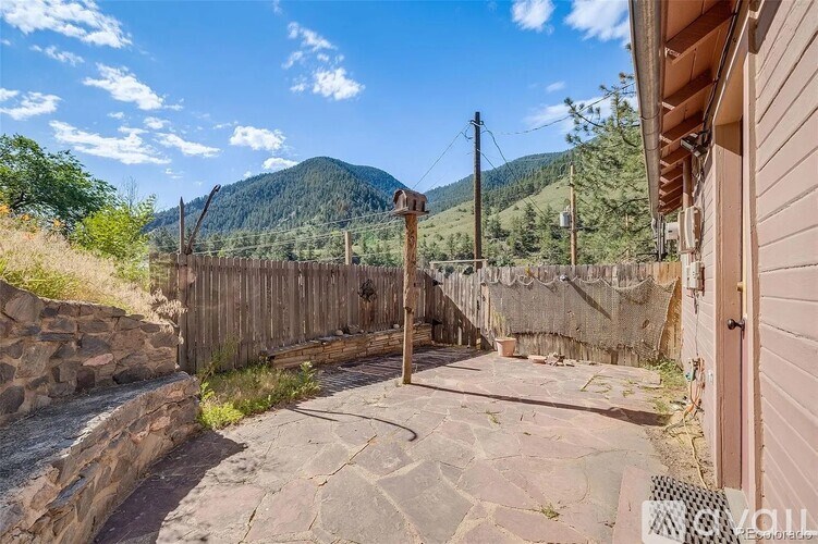 A backyard with a wooden fence and a stone pathway leading to a house.