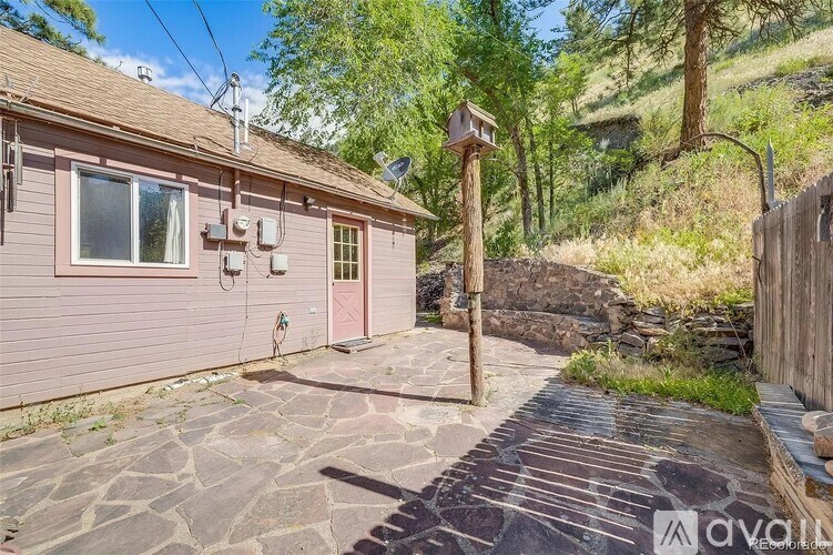A house with a pink exterior and a stone pathway leading to a wooden fence.