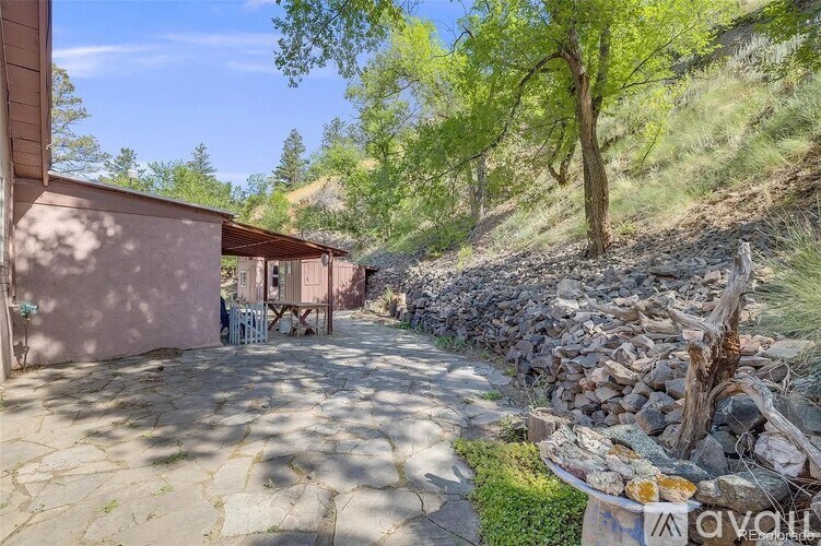 A stone wall borders a patio with a table and chairs.