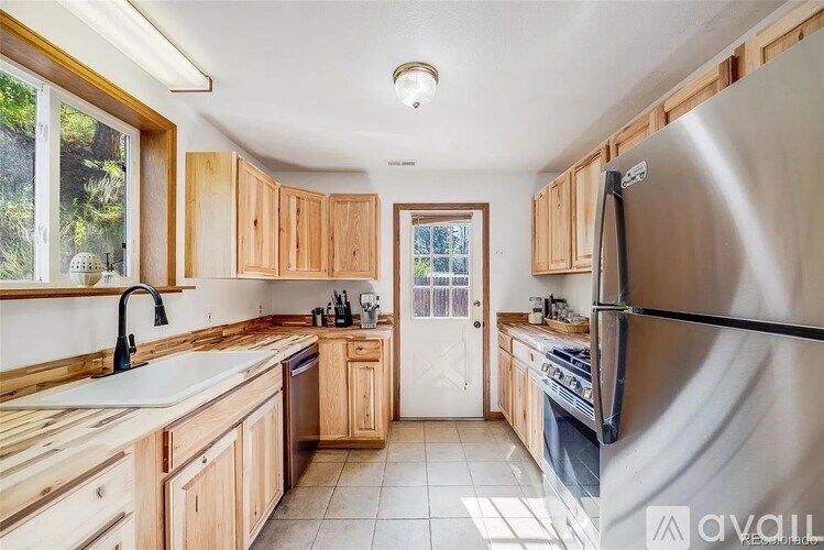 A kitchen with wooden cabinets and a stainless steel refrigerator.