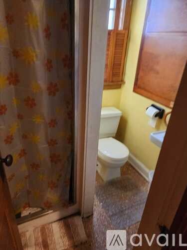 A bathroom with a toilet, a shower curtain, and a towel rack.
