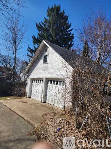 A white house with a grey roof and a white garage door.
