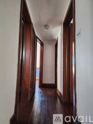 A hallway with wooden floors and white walls.