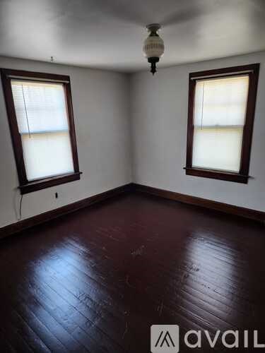 A room with two windows and a wooden floor.