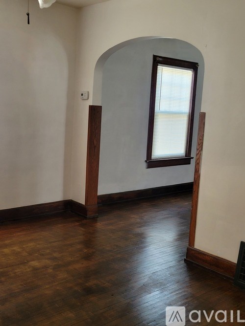 A room with a wooden floor and a window with blinds.