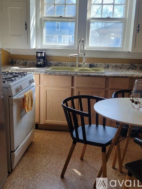A kitchen with a stove, sink, and a chair.