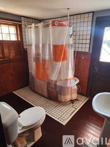 A bathroom with a toilet, a shower curtain, and a tiled floor.