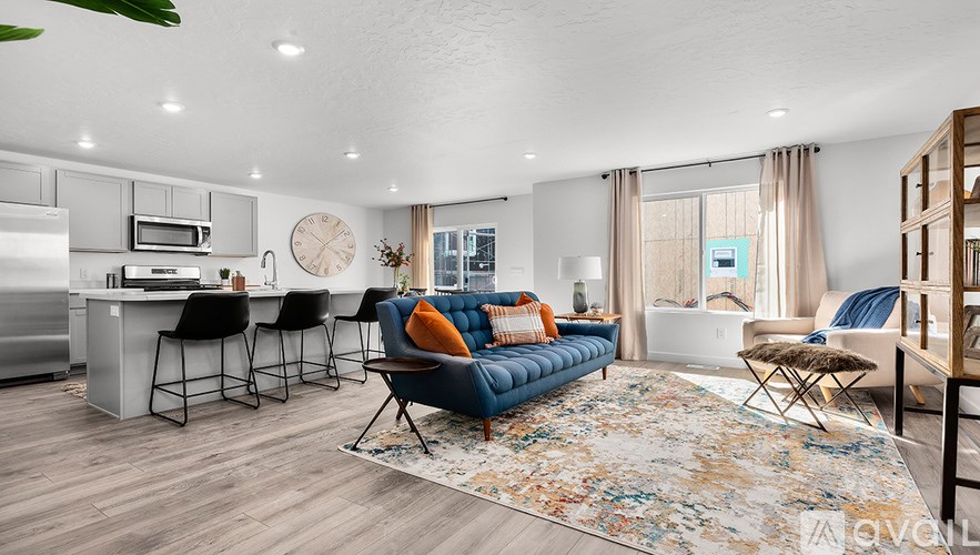 A modern living room with a blue sofa and a kitchen area in the background.
