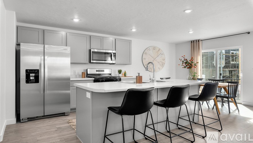 A modern kitchen with a refrigerator, microwave, oven, and sink.