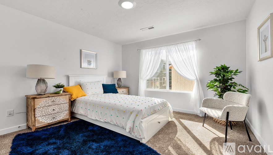 A bedroom with a bed, chair, and a plant.