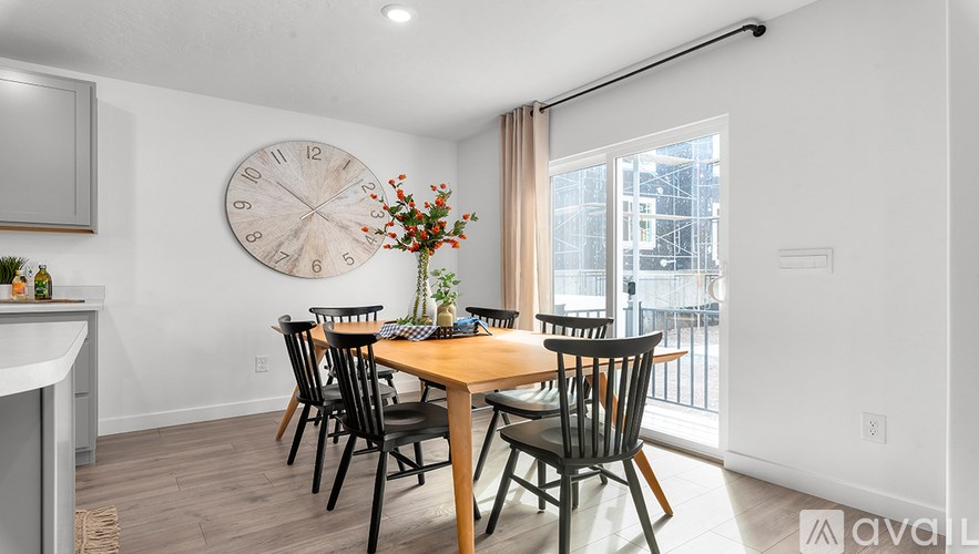 A dining room with a large clock on the wall and a table set for six.