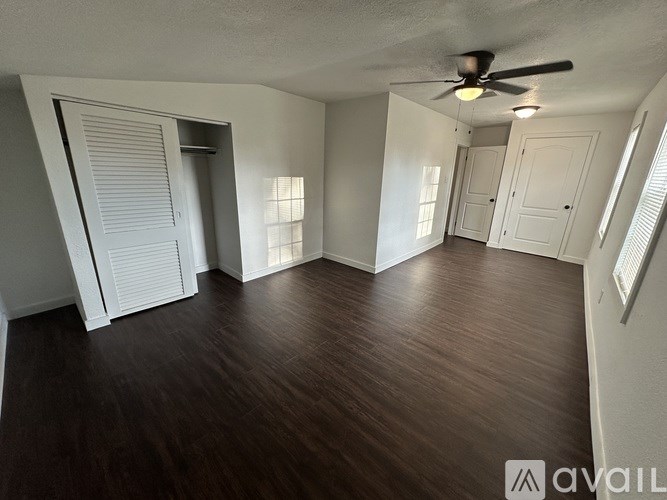 A room with a ceiling fan and wooden flooring.
