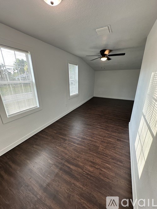 A room with a ceiling fan and wooden flooring.