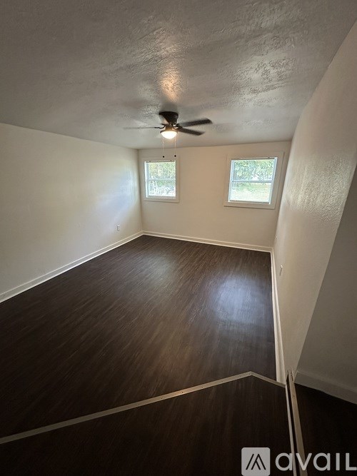 A room with a ceiling fan and wooden flooring.