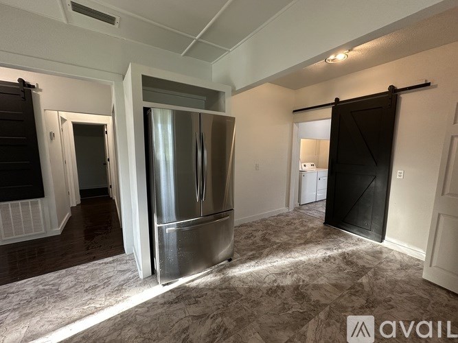 A kitchen area with a stainless steel refrigerator and a carpeted floor.
