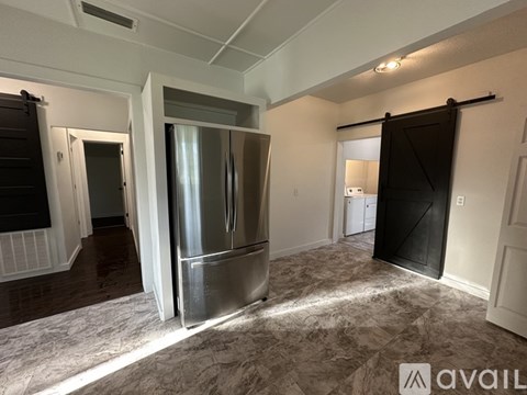 A kitchen area with a stainless steel refrigerator and a carpeted floor.