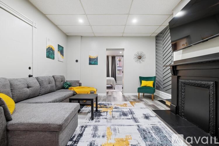 A living room with a grey couch, yellow pillows, and a fireplace.