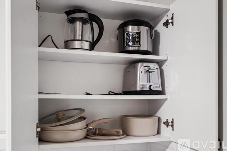 A kitchen cabinet with a coffee maker and toaster on the shelf.