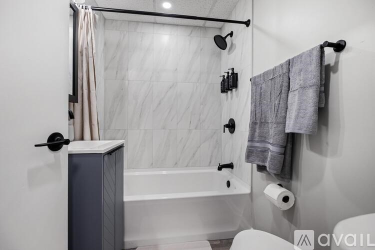 A bathroom with a white tub and grey towel.