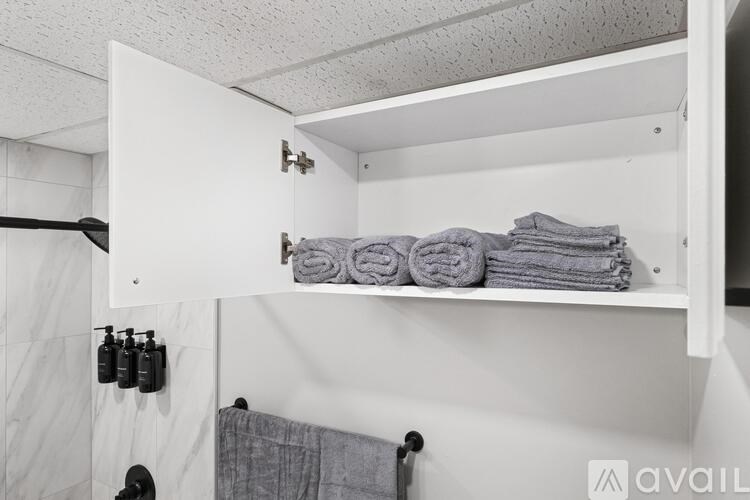 A white bathroom with towels and toiletries on the shelf.