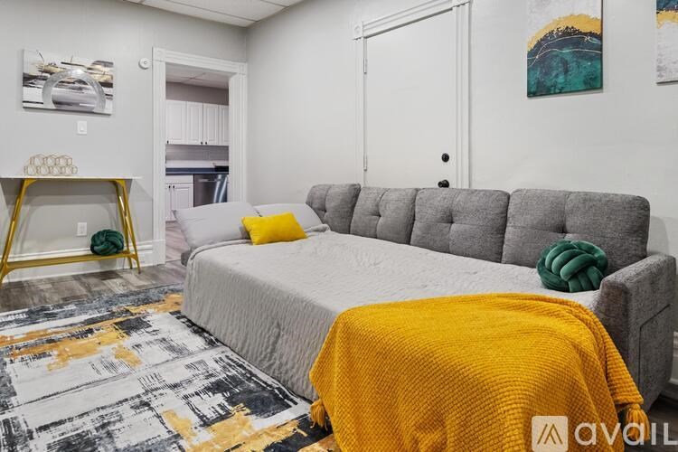 A bedroom with a grey bed and a yellow throw.