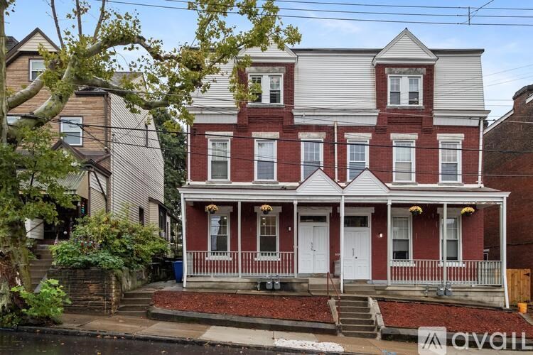 A two-story house with a red and white exterior and a porch.