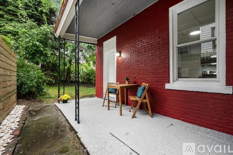 A red building with a white door and a small table and chairs outside.