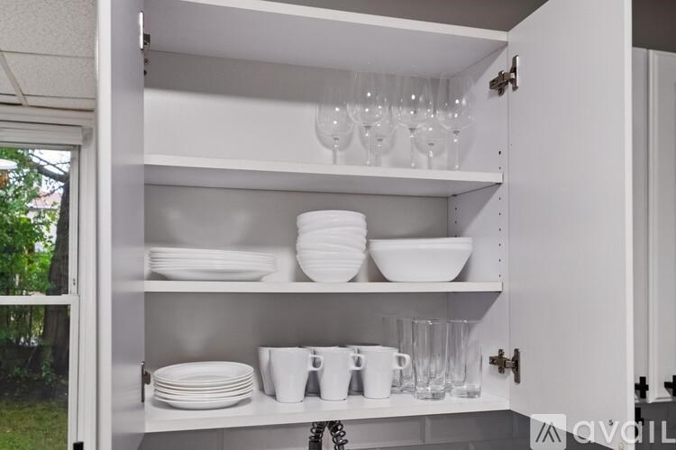 A white cabinet with plates and glasses on the shelves.