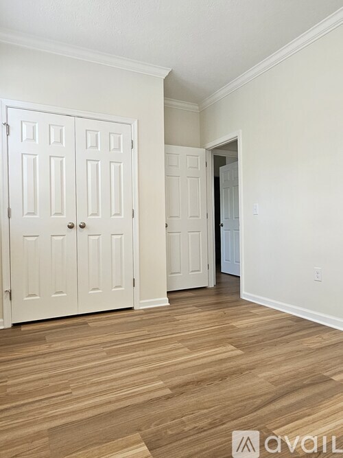 A room with a white door and wooden flooring.
