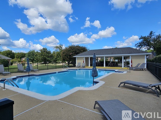 A swimming pool with lounge chairs and a house in the background.