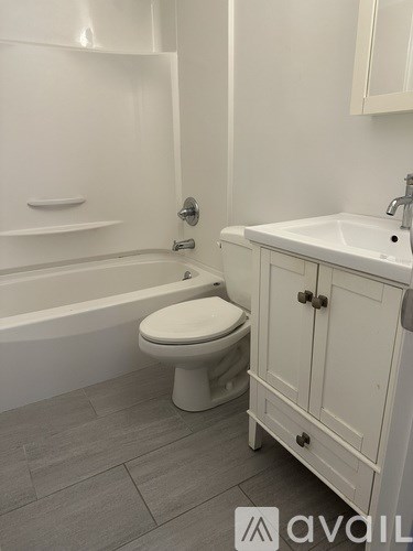 A white toilet sits in a bathroom next to a sink.