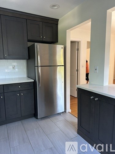 A kitchen with a stainless steel refrigerator and black cabinets.