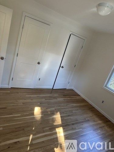 A room with white doors and wooden flooring.