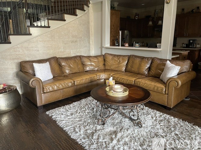 A brown leather sofa with a coffee table in front of it.