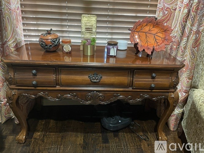 A wooden table with a leaf decoration and various objects on it.