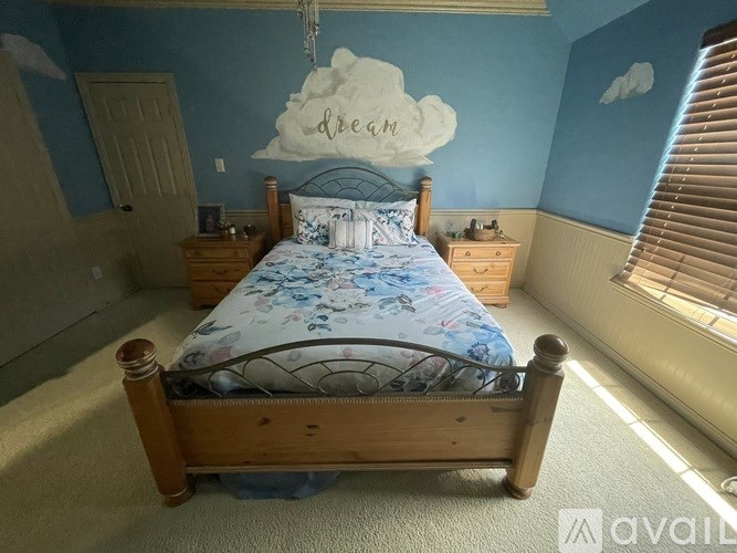 A bedroom with a bed, nightstands, and a dream cloud mural.