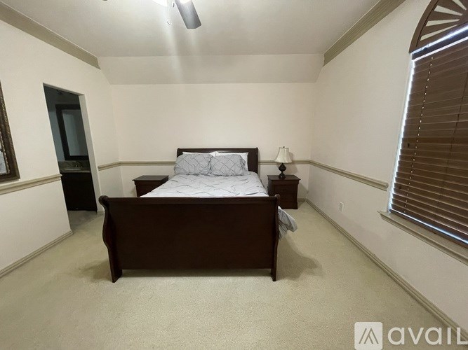 A bedroom with a bed, nightstand, and window with blinds.